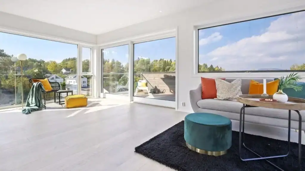 Bright modern living room with large windows and scenic views, stylish decor, and contemporary furniture.