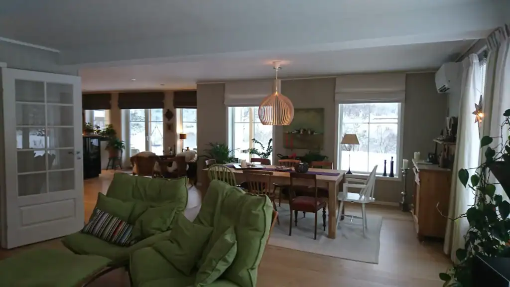 Lys stue med moderne innredning, store vinduer, grønne planter og koselig atmosfære, perfekt for boligutvikling og eiendomsinvesteringer.