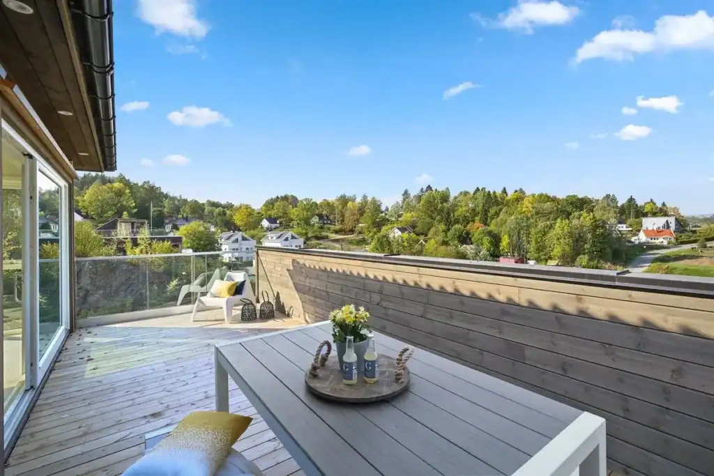 Moderne terrasse med utsikt over grønn natur og boligområder, ideell for avslapning og utendørs hyggestunder, fokus på innovativ boligutvikling fra Ageco.
